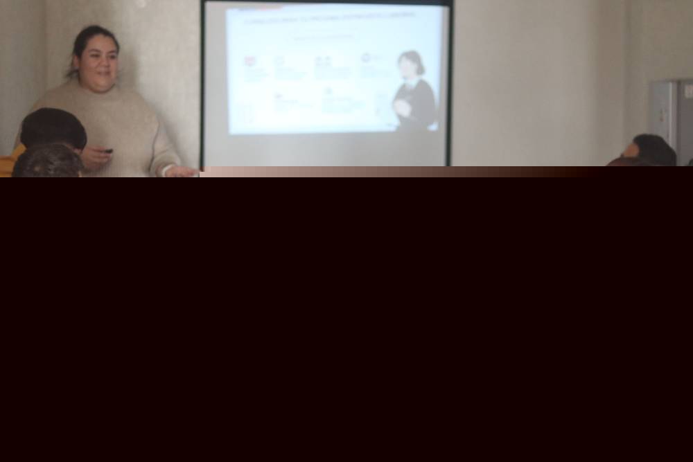 Jóvenes participan en un taller de búsqueda de empleo junto a una facilitadora frente a una pantalla de proyección